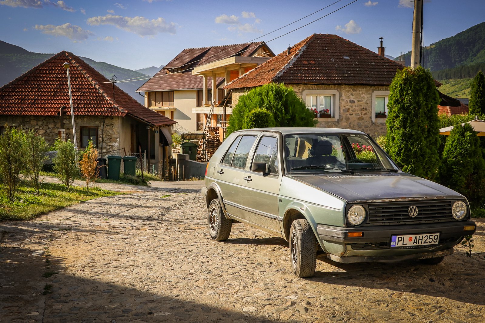 A grey hatchback parked on a cobbled village road