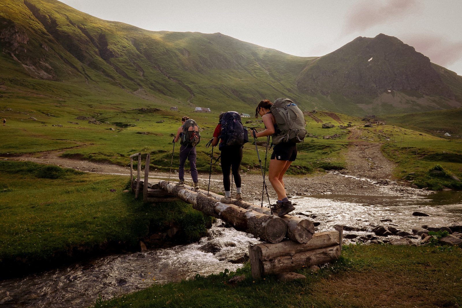 Hikers cross a log bridge over a stream