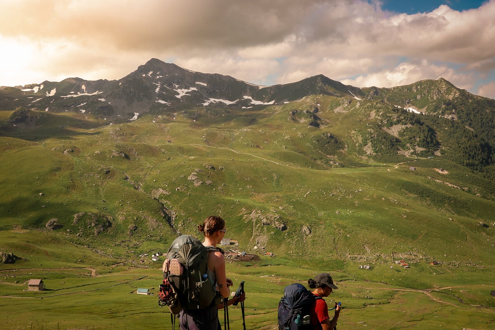 Two hikers crossing a high meadow below a ridge