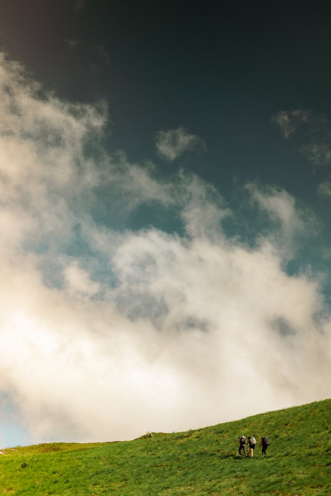 Storm cloud towering over a tiny line of hikers
