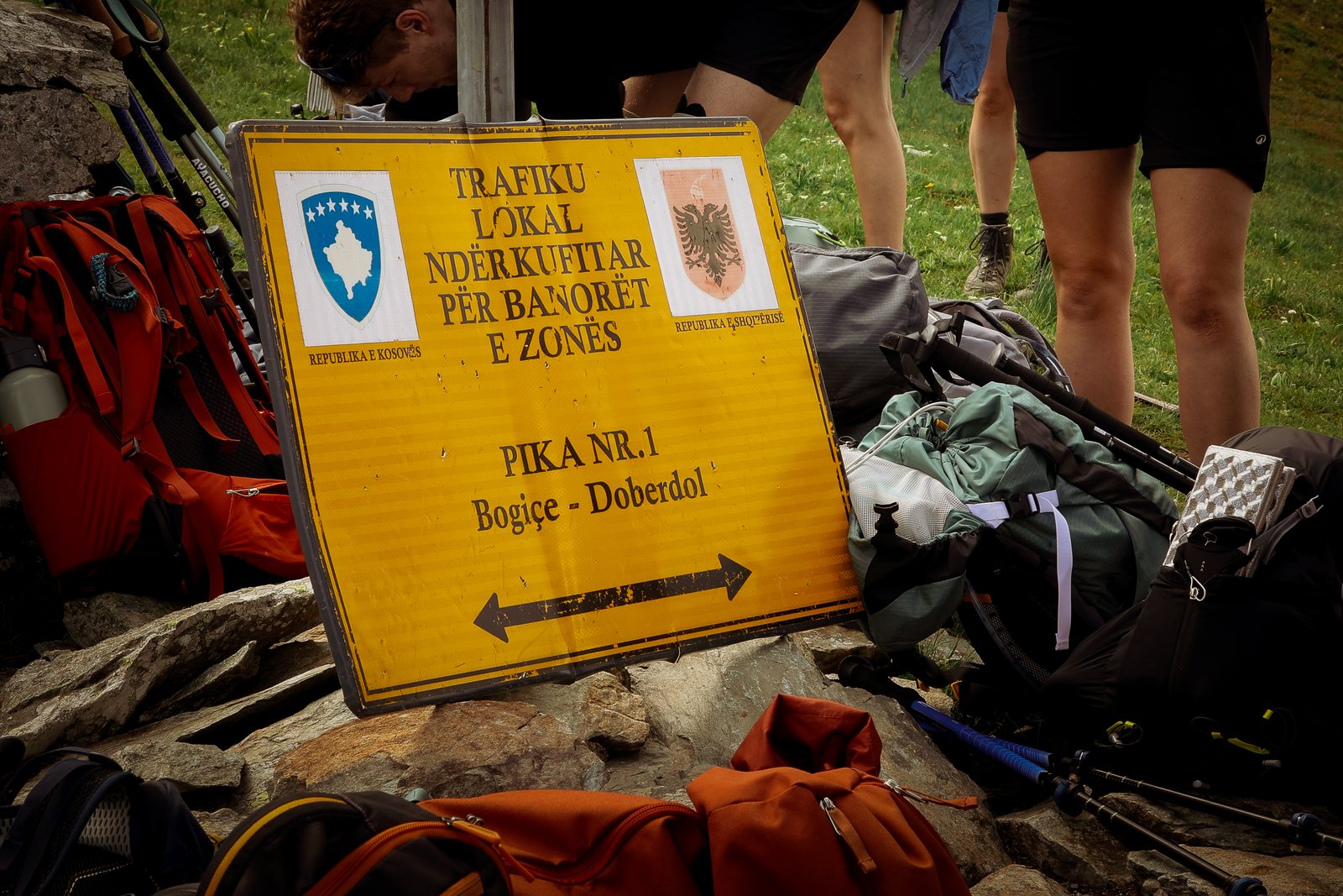 A border crossing sign propped among hiking gear