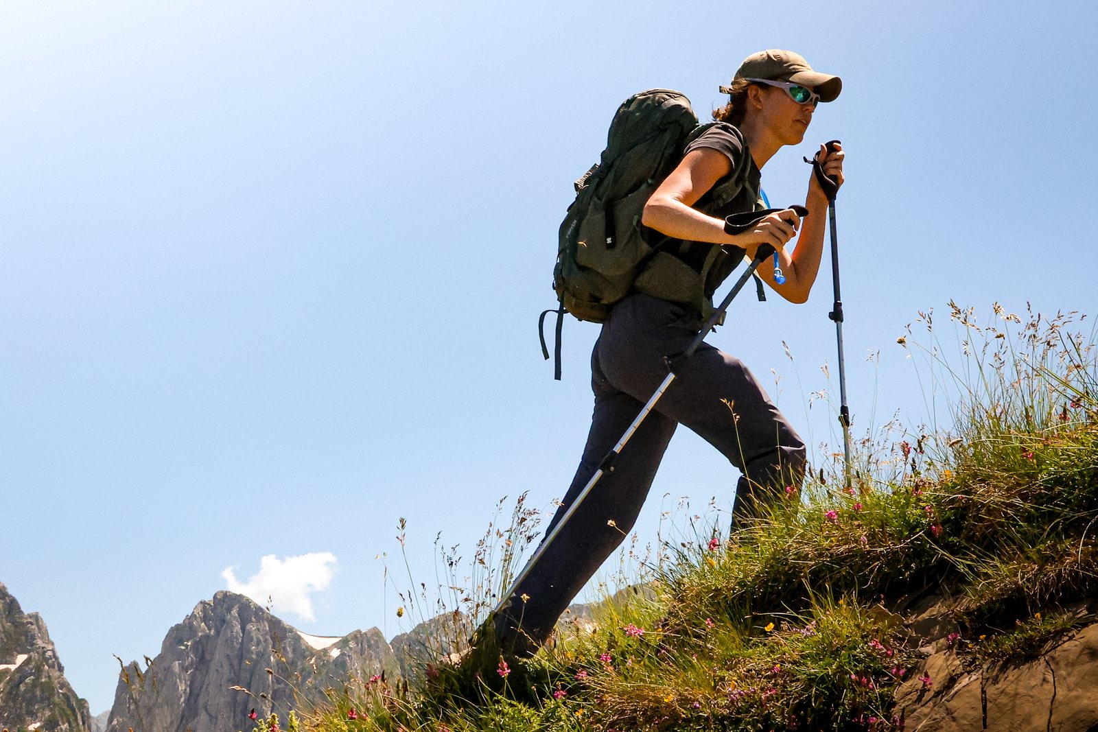 A hiker with trekking poles against blue sky