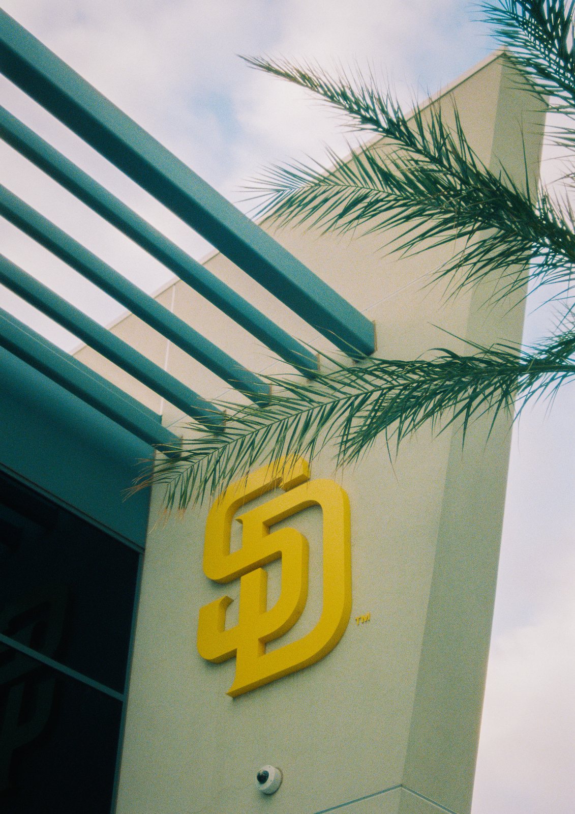 A Padres logo on a stadium wall below palm fronds