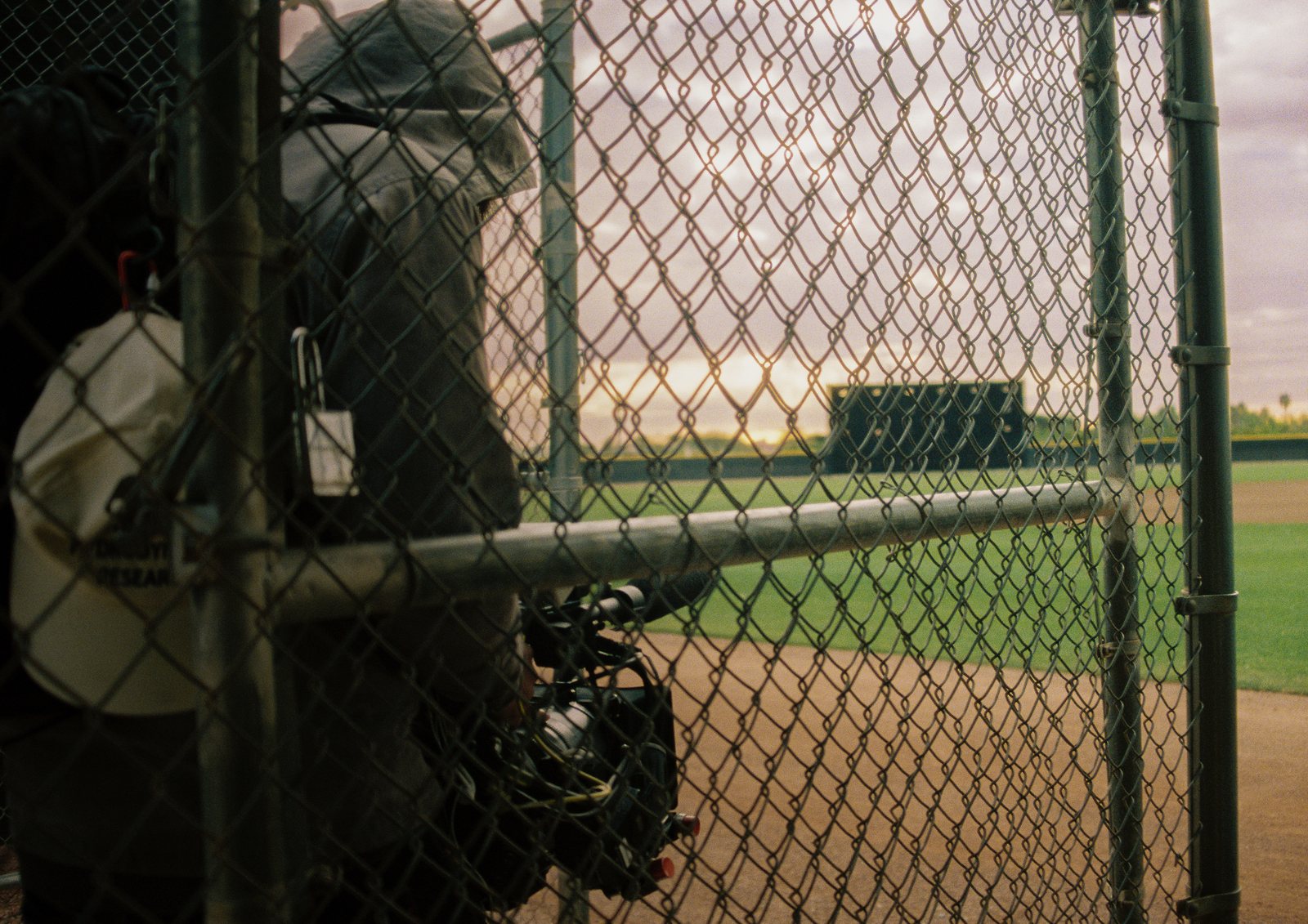 A camera operator shooting through the dugout fence