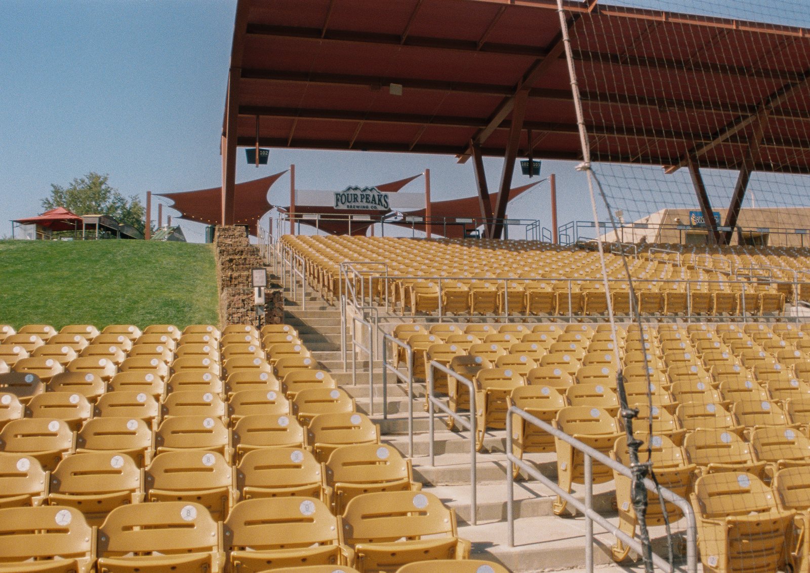 Rows of empty yellow stadium seats under a shade canopy
