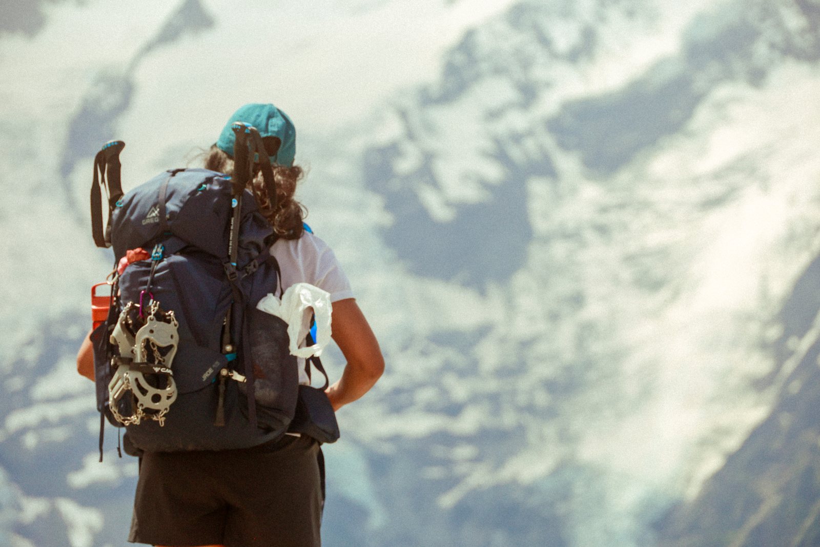 A hiker with a loaded pack looks out over a glacier