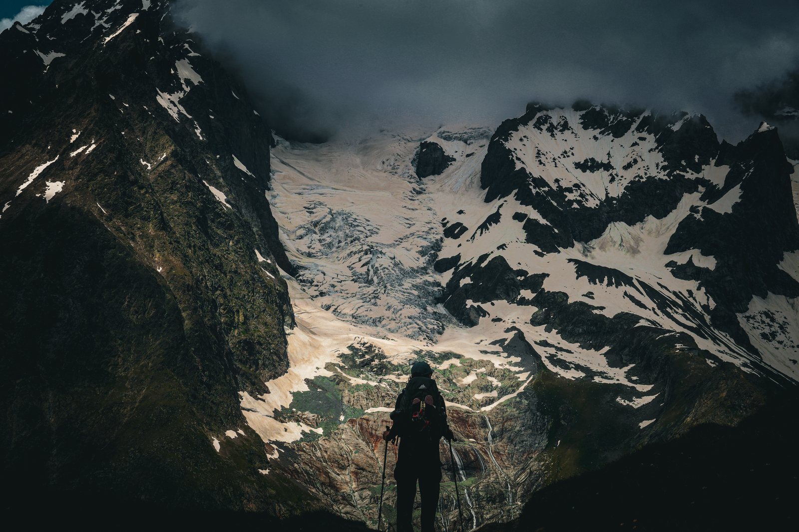 A figure stands below a glacier