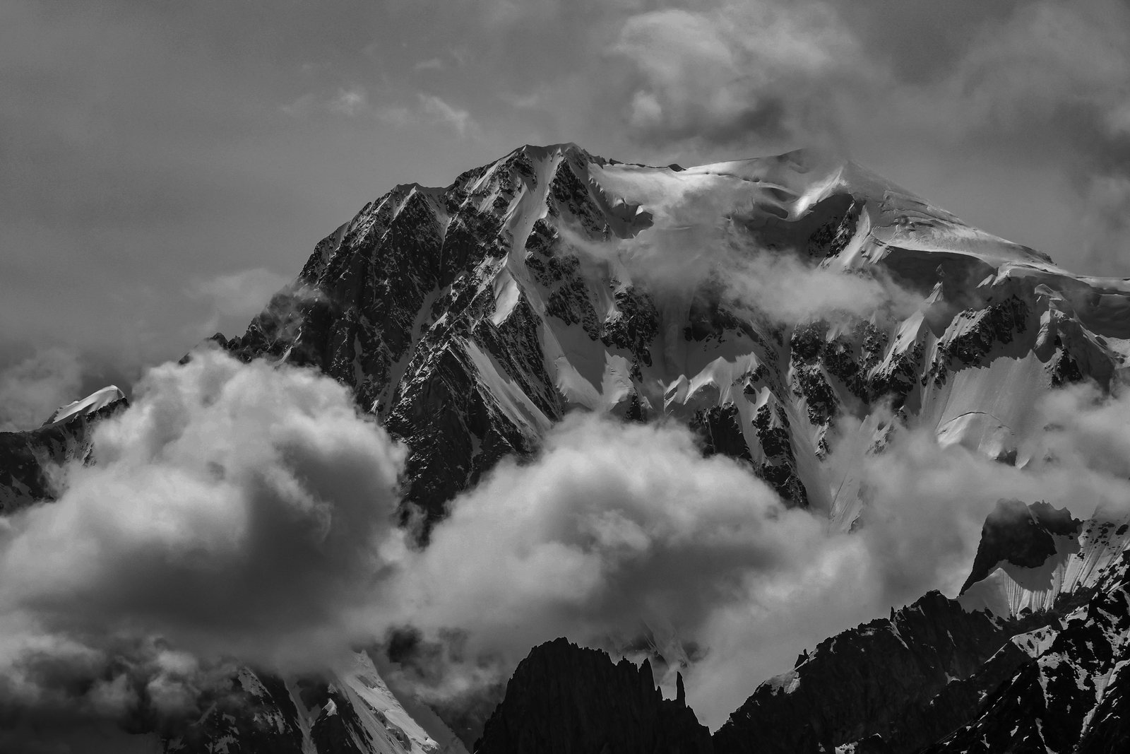 Black and white view of a snow peak above clouds