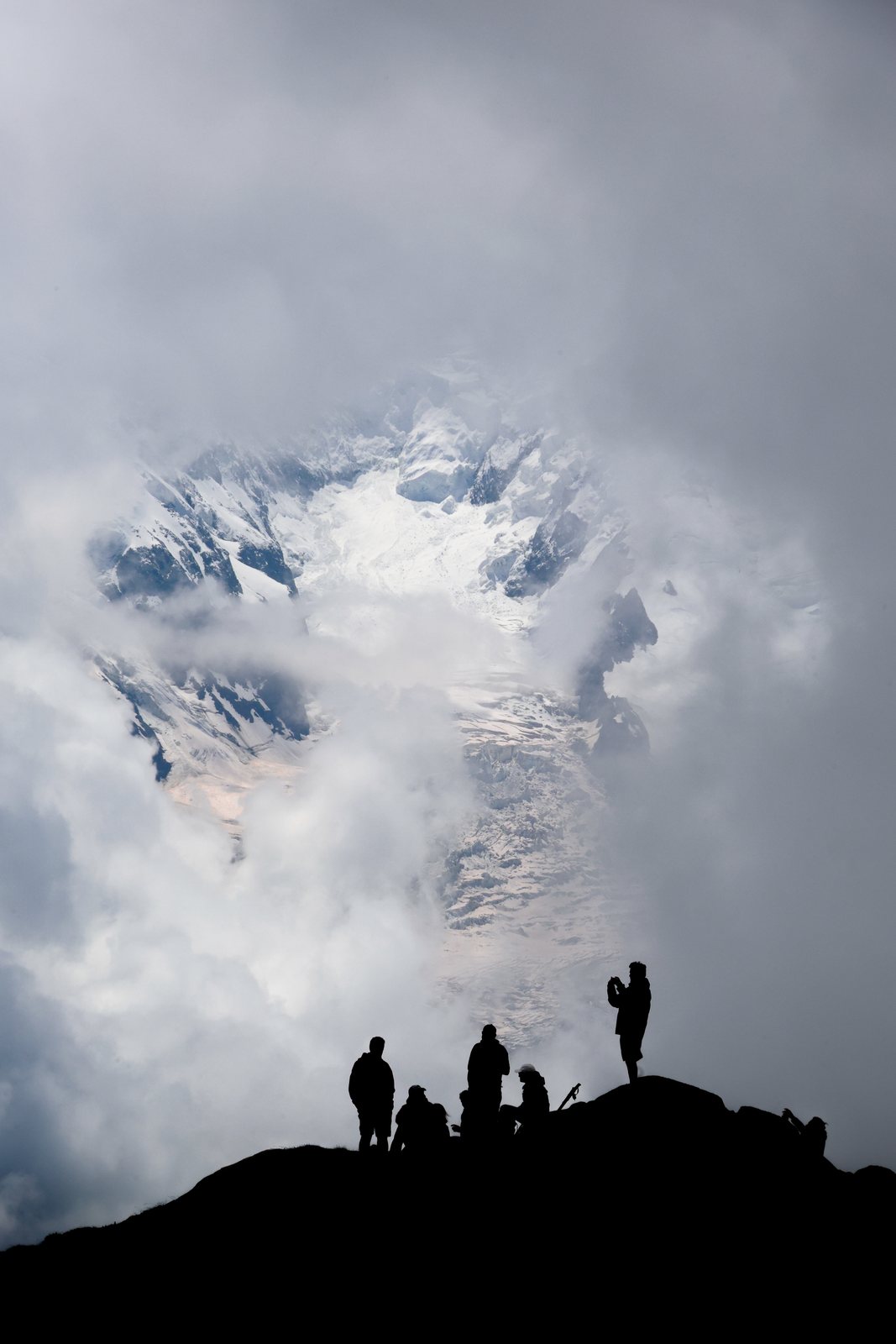 Silhouetted hikers on a ridge against cloud