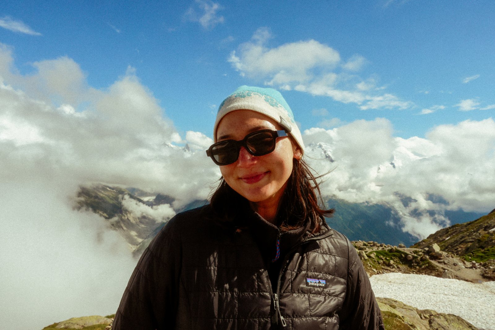 A smiling hiker in sunglasses above the clouds