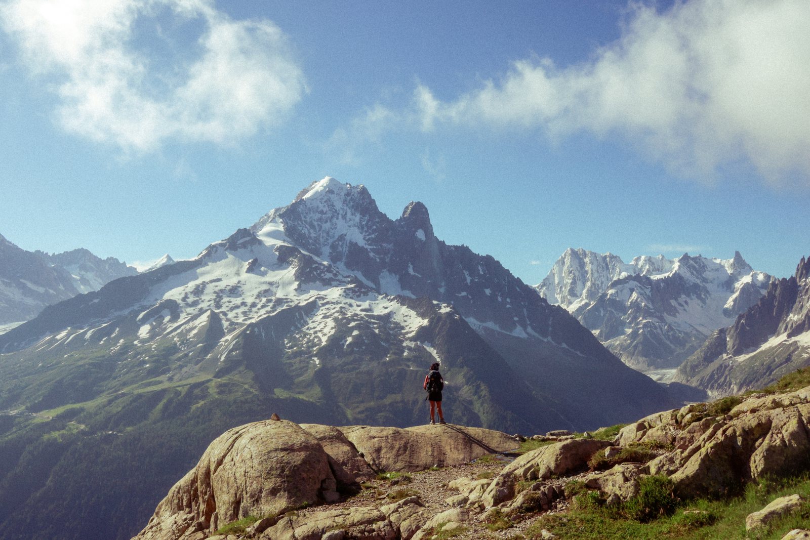 A lone figure at a viewpoint facing a snow peak