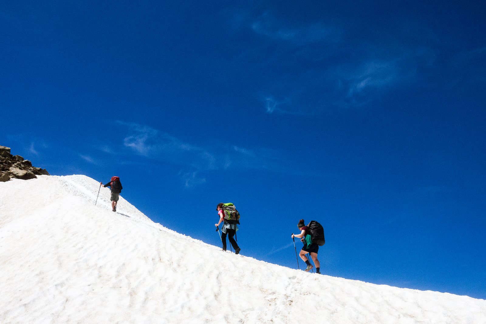 Hikers on a snow slope under deep blue sky