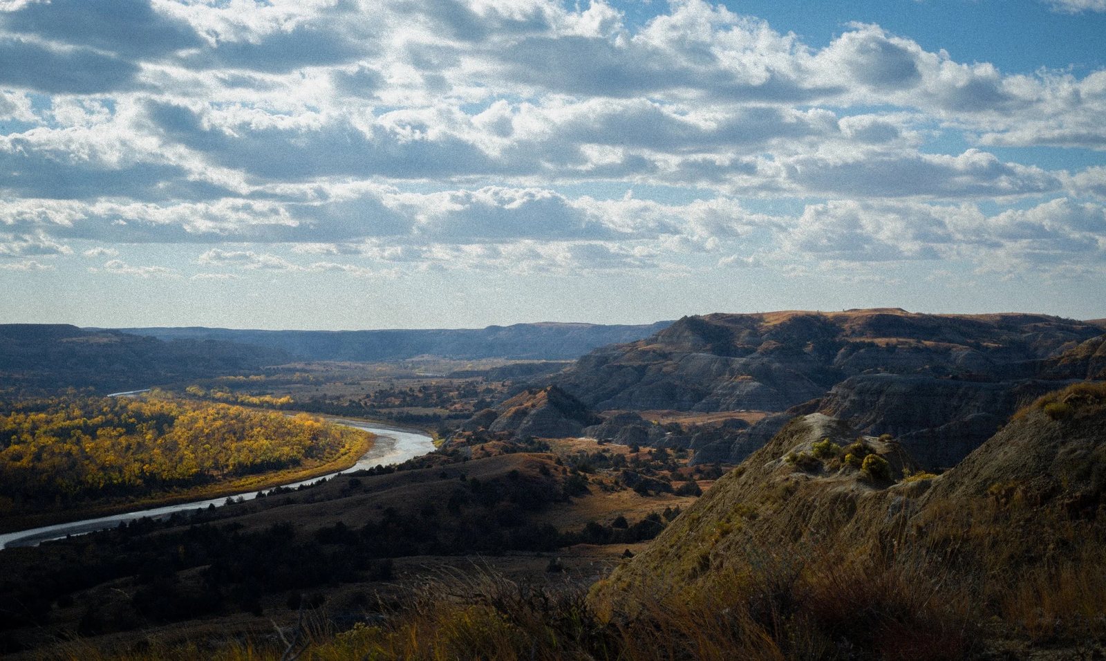 A river bends through badlands under heavy cloud