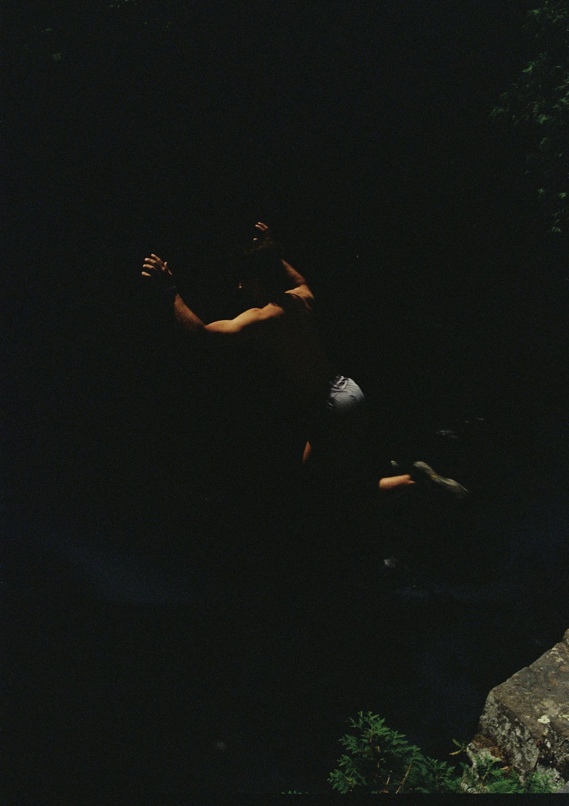 A dark film frame with faint figures and light