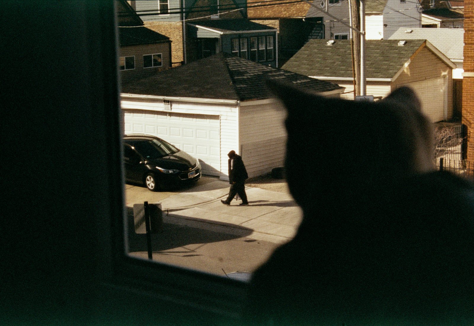 A man walking in an alley, seen through a window